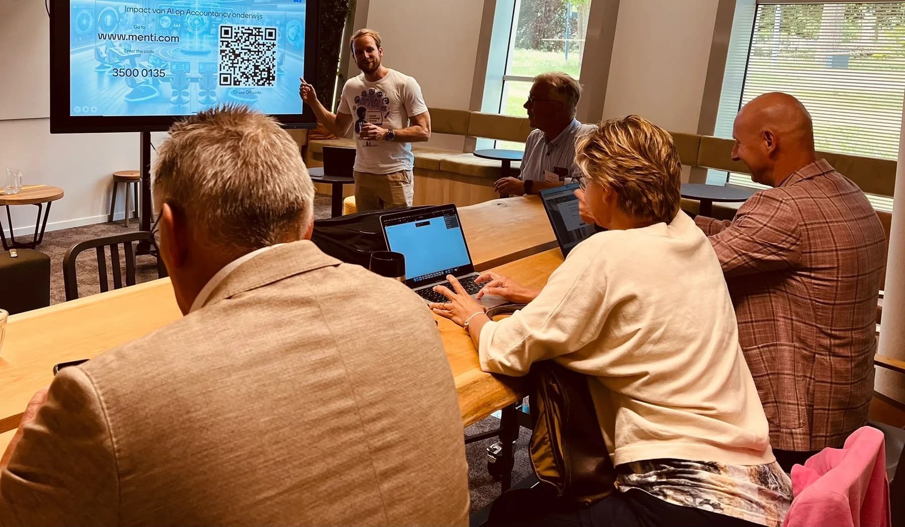 Tom Naberink begeleidt een praktische AI-workshop met onderwijsprofessionals die op hun eigen laptops werken.